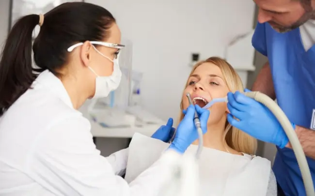 Patient undergoing root canal treatment in Muscat while dentists use dental instruments and suction equipment during an advanced endodontic procedure.